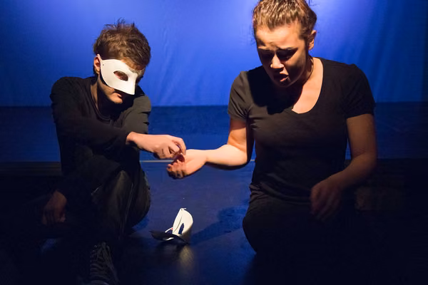 Two people with theatre masks on a stage