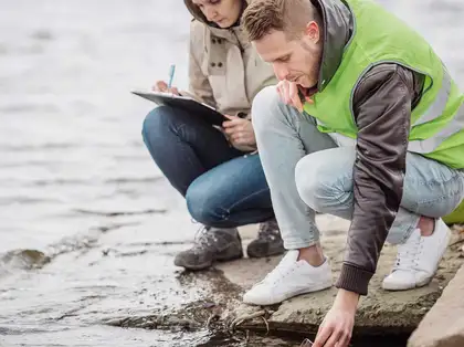 Two people inspecting water at a waterfront