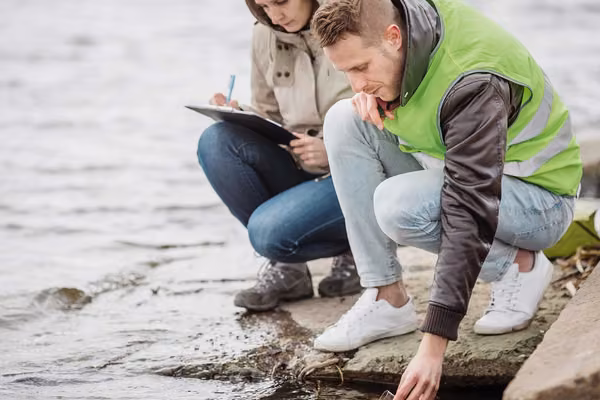 Two people inspecting water at a waterfront