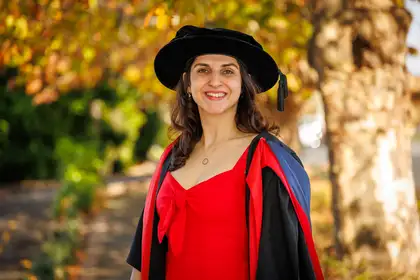 woman in graduation gown and hat smiling