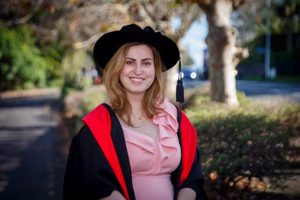Woman in graduation regalia smiling at camera