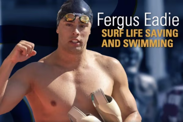 man in swim cap and googles holding up fist