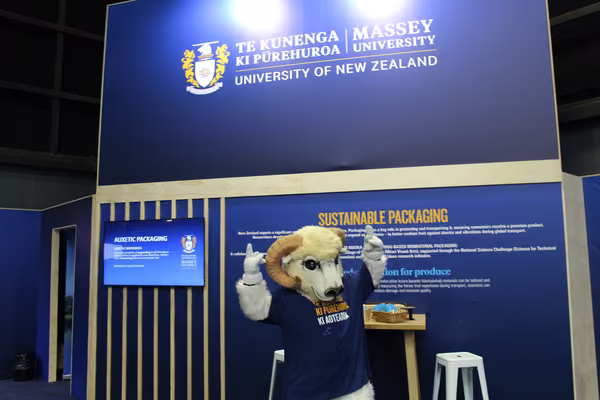 ram mascot standing in front of blue Massey sign
