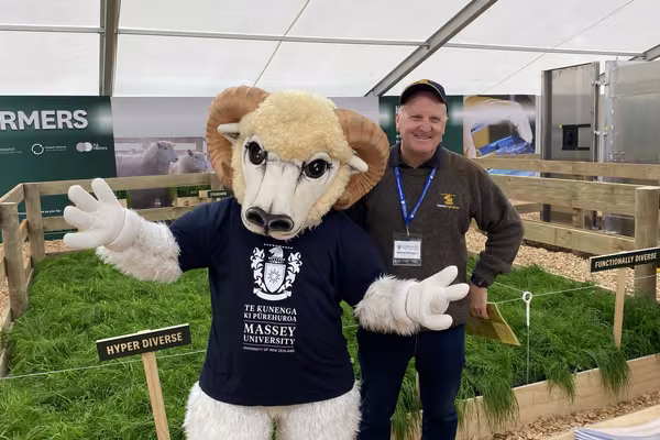 Man and ram mascot costume standing together in front of grass