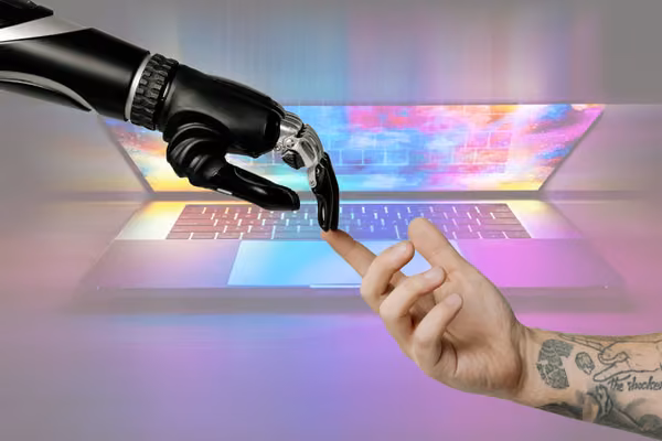 Half closed laptop with robotic hand and human hand touching fingertips.