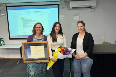 Dr Lynsey Ellis, recipient Grace Amick and Field Educator Candice Young standing together holding flowers and the framed award.