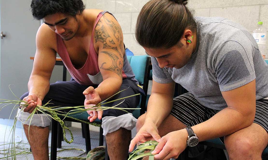 Two students weaving with flax