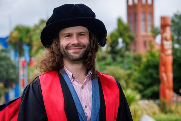 man wearing doctoral robes smiling
