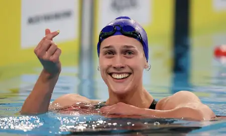 Hazel Ouwehand in the pool smiling and making a heart with her thumbs.