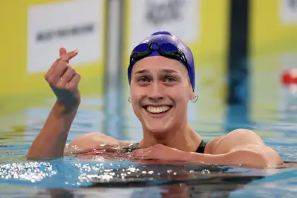 Hazel Ouwehand in the pool smiling and making a heart with her thumbs.