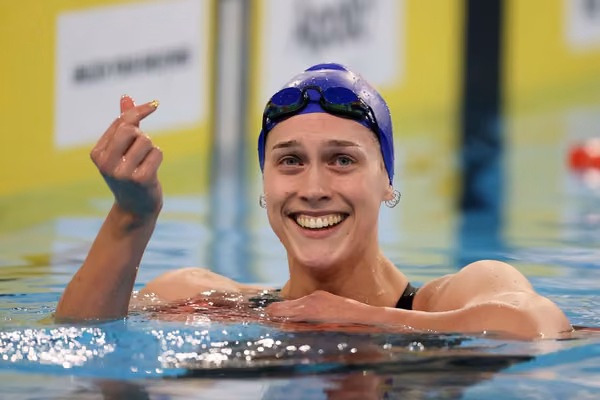 Hazel Ouwehand in the pool smiling and making a heart with her thumbs.