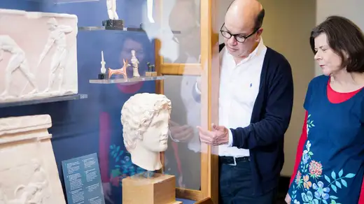 Two people regard a Grecian bust in a display case