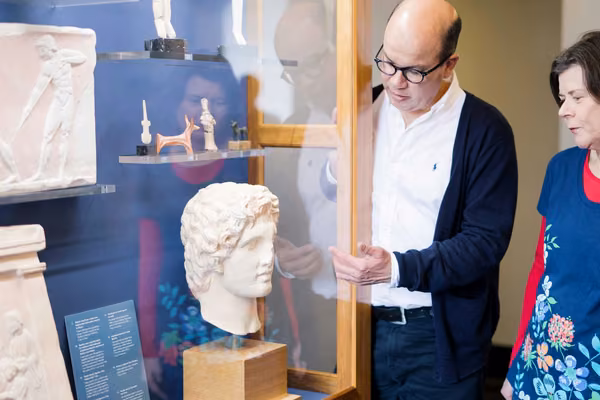 Two people regard a Grecian bust in a display case