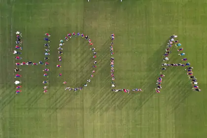 Local footballers spell out "Hola" on the pitch of the Sports Institute.