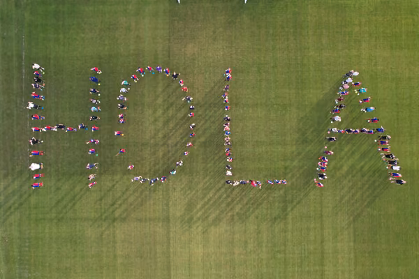 Local footballers spell out "Hola" on the pitch of the Sports Institute.