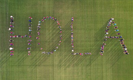 Local footballers spell out "Hola" on the pitch of the Sports Institute.