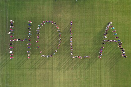 Local footballers spell out "Hola" on the pitch of the Sports Institute.