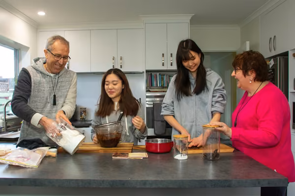 Homestay students cook in the kitchen with their host family.