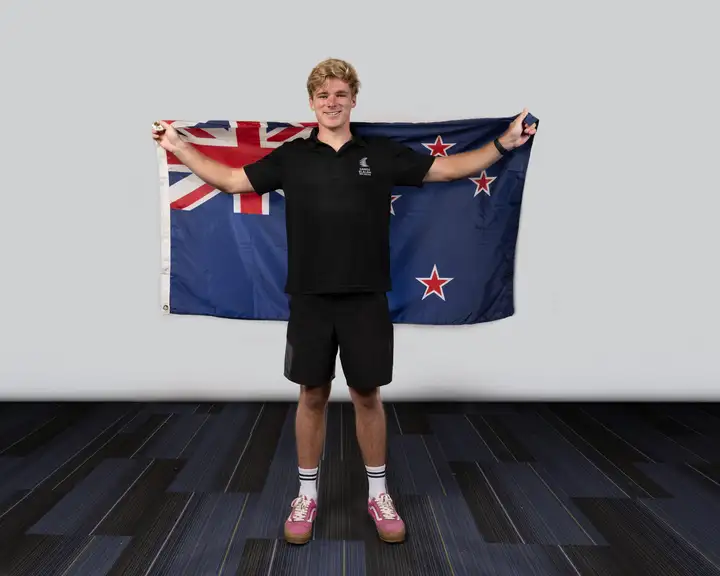 man holding New Zealand flag behind him