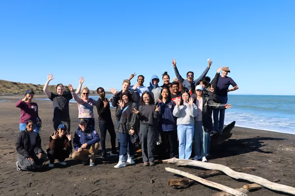 group of people standing on the beach smiling at camera