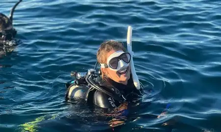 Girl in the ocean smiling and wearing scuba gear.