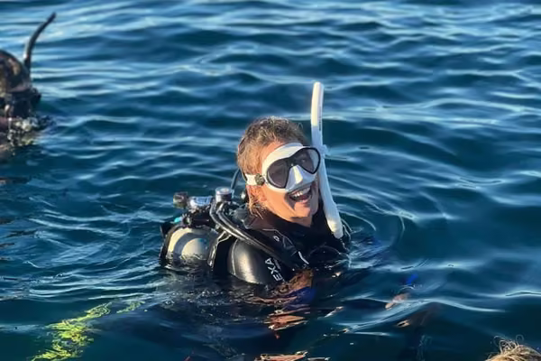 Girl in the ocean smiling and wearing scuba gear.
