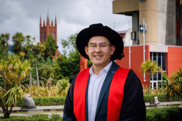 man in doctoral graduation gown smiling