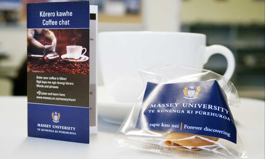 Close-up of a coffee cup and a pamphlet on how to order coffee in te reo Māori