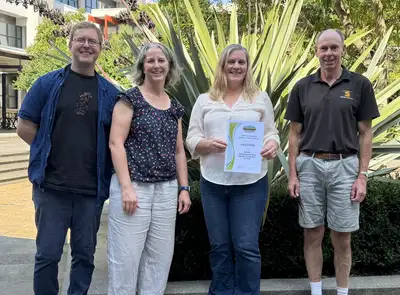 group of people standing outside smiling one holding certificate