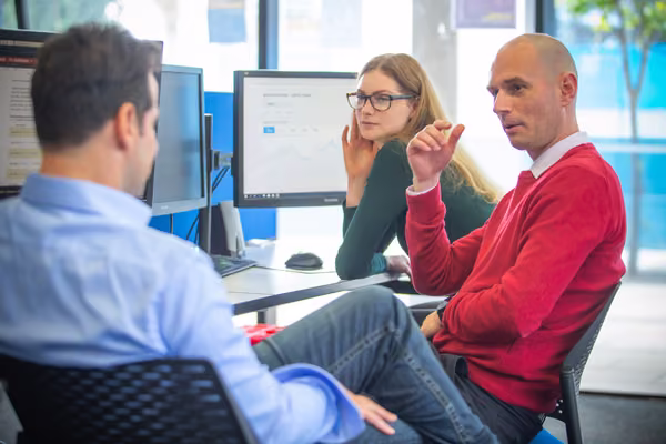 Three people talking whilst sitting in front of a computer