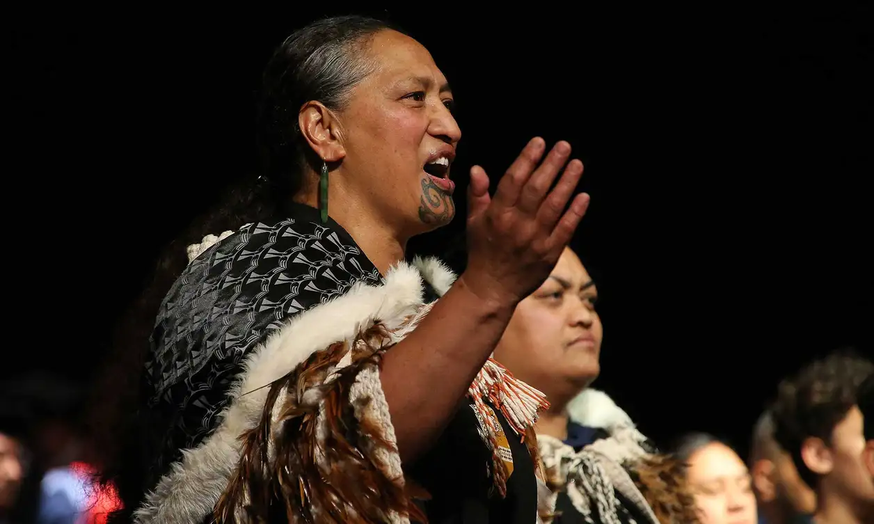 Person dressed in traditional Māori cloak singing a Māori song or waiata