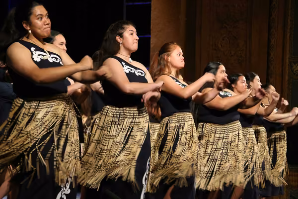 Group of women performing a waiata, dressed in full traditional Maori costume