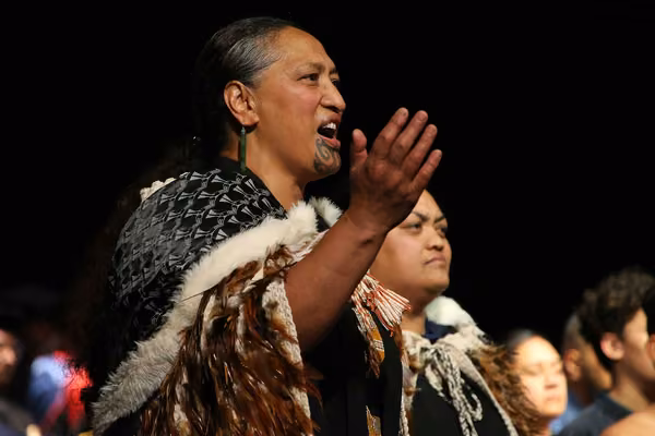 Person dressed in traditional Māori cloak singing a Māori song or waiata
