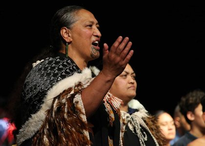 Person dressed in traditional Māori cloak singing a Māori song or waiata