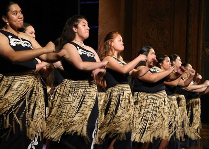 Group of women performing a waiata, dressed in full traditional Maori costume