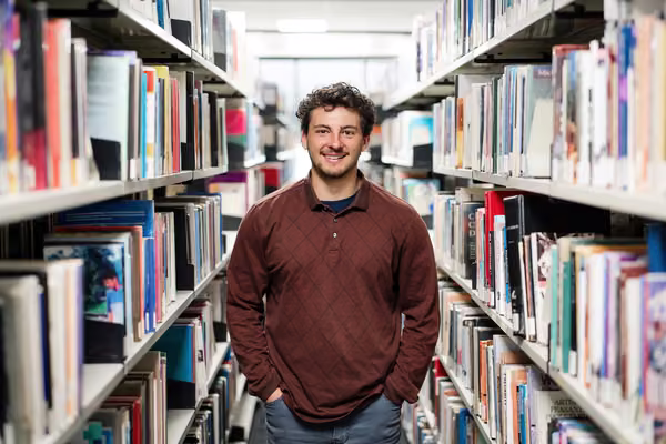 Student standing in library isle.