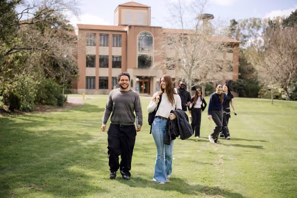 Group of students on campus walking across field.