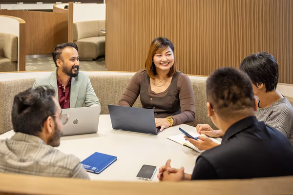 Five people sitting in a circle around a table.