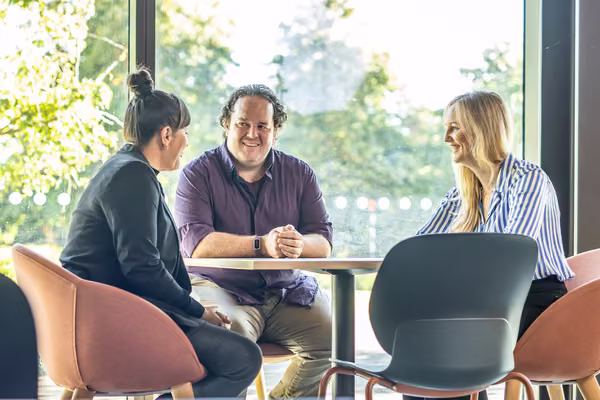 Three people sitting smiling at a table.