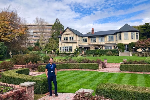 man standing outside in garden of historic house