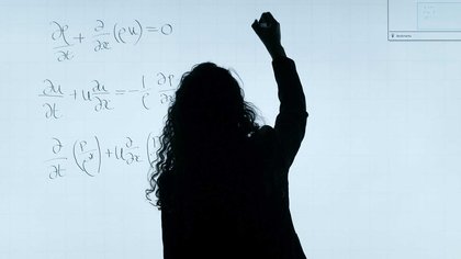 Silhouette of person writing equations on whiteboard