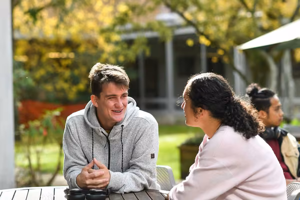 Two people talking at an outdoor table