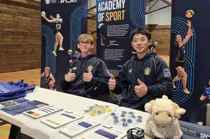 two student athletes sitting at a table surrounded by Sport Massey banners