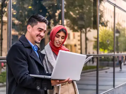 Two international students looking at a laptop.