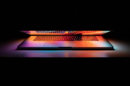 Image of a half open laptop in the dark.
