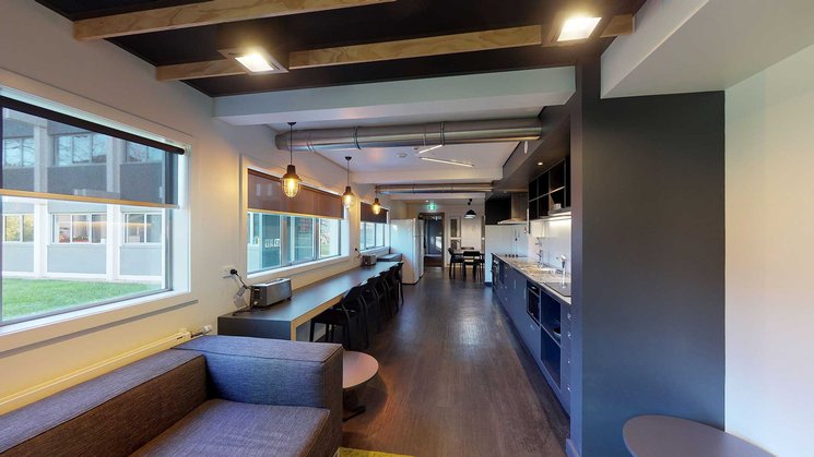 Interior of Walter Dyer Hall's kitchen with a long bench top and a long built in table with chairs