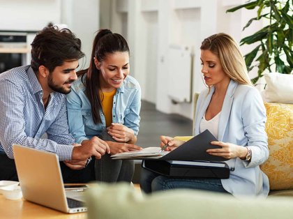 Three smiling people look at notes in a folder