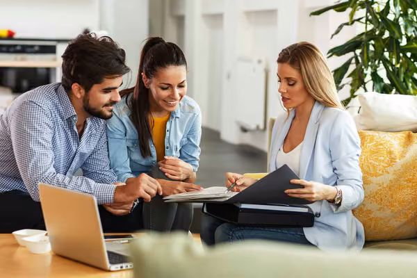 Three smiling people look at notes in a folder
