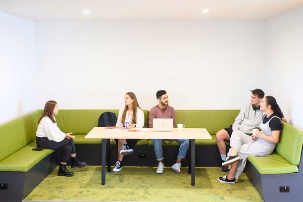 Two small groups of young people talking and having coffee