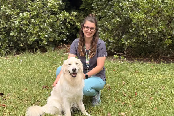 veterinary nurse sitting outside on grass with dog